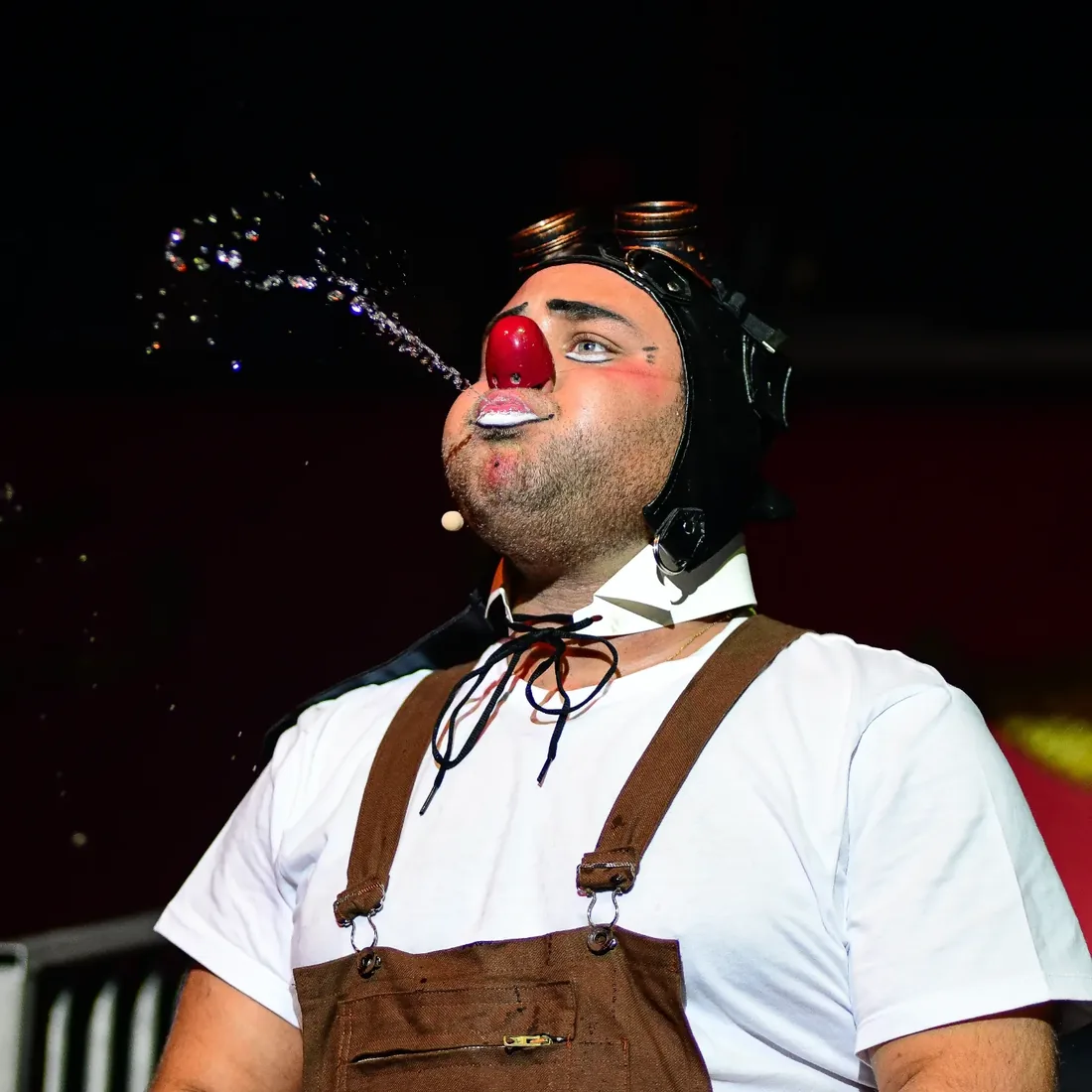 Numéro comique du clown recrachant de l'eau, sous les rires des enfants.